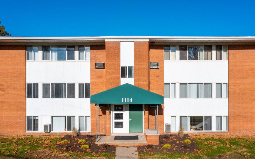 the front of a brick building with a green front door